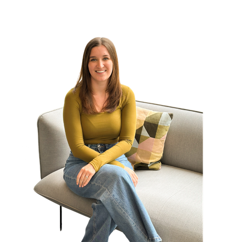 A striveX team member smiling while sitting on a sofa