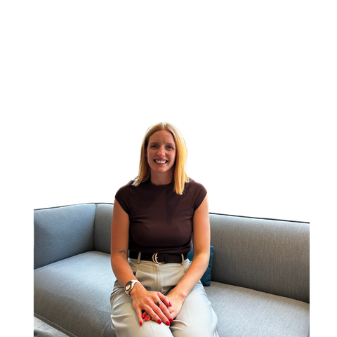 A striveX team member smiling while sitting on a sofa