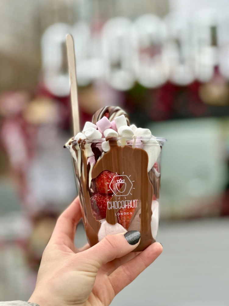 Chocolate-dipped strawberry dessert cup topped with marshmallows in a branded Chocofruit London cup